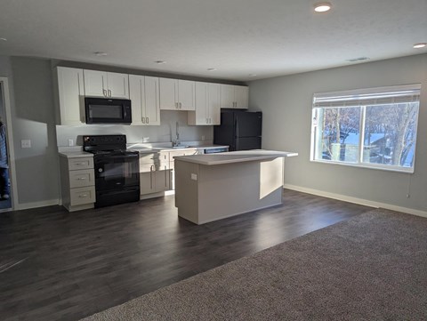 an empty kitchen with white cabinets and black appliances